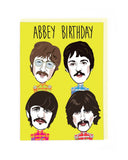 Card with illustrations of The Beatles on a yellow background, featuring the text 'Abbey Birthday'.