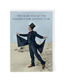 Person in a suit and top hat on a beach with text 'The older you get, the madder you're allowed to be'.